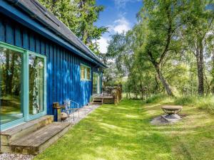 una casa blu con una panchina accanto a un cortile di Ptarmigan Cottage-ukc5518 a Boat of Garten