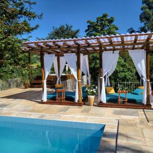 uma pérgola de madeira junto a uma piscina em Hotel La Bella Toscana - Exclusive Hotel em Águas de Lindóia