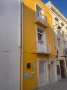 a yellow building with a balcony on the side of it at PEROLA DA MUSICA ESTUDIO in Setúbal