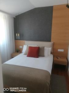 a bedroom with a large white bed with a red pillow at Timeless - Energy - Belém in Lisbon