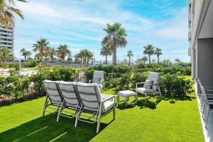Una fila de sillas y mesas en un césped con palmeras. en Apartment Grape Panorama Mar, en Punta Prima