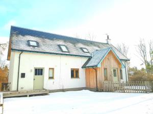 Una casa blanca con una valla de madera en la nieve. en The Byre - by Where Stags Roar, en Newtonmore