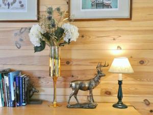 un jarrón con un ciervo en una mesa junto a una lámpara en The Byre - by Where Stags Roar, en Newtonmore
