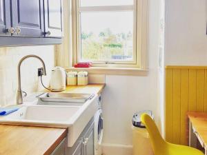 uma pequena cozinha com um lavatório e uma janela em Caman House Apt 2 - by Where Stags Roar em Newtonmore