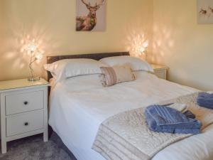 a bedroom with two beds and a night stand with two lamps at The Old Croft House in Strontian