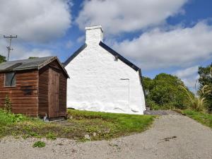 un edificio blanco con un pequeño cobertizo al lado en The Old Croft House en Strontian