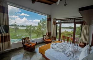 a bedroom with a bed and a large window at Sigiriya Wewa Addara Hotel - Hotel By The Lake in Sigiriya