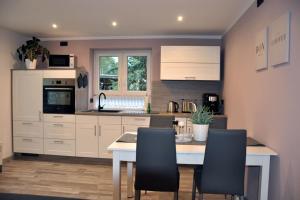 a kitchen with white cabinets and a table with chairs at -Haus am Wäldchen- in Zehdenick