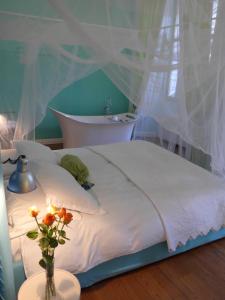 a white bed with a vase of flowers on a table at B&B Casa Fenoglio in Ventimiglia