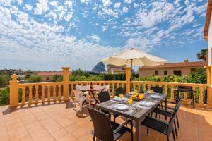 een patio met een tafel en stoelen en een parasol bij Villa Serena - PlusHolidays in Calpe