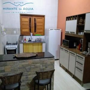 a kitchen with a counter with two chairs and a refrigerator at Suítes Mirante da Águia in Ibicoara