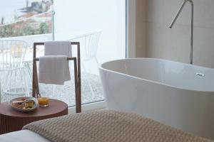 a bathroom with a bath tub and a balcony at Otantus Hotel in Muros