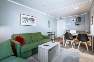a living room with a green couch and a table at Birkebeineren Hotel & Apartments in Lillehammer