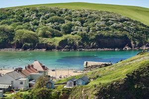 a group of houses on a beach next to a body of water at Hope & Anchor in Hope Cove