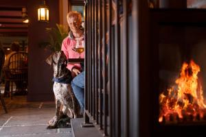 a man and his dog sitting in front of a fireplace at Hope & Anchor in Hope Cove