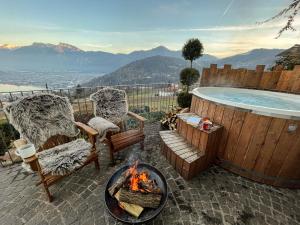 una hoguera con 2 sillas y una bañera de hidromasaje en Alpinlake Lodge & Wellness, en Bosentino