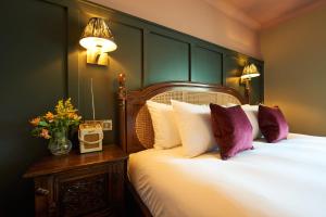 a bedroom with a bed with white sheets and purple pillows at Hope & Anchor in Hope Cove