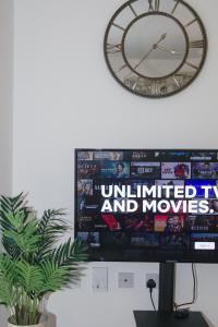 a large clock on a wall above a television at Cosy 2-bed home - For Company contractor and Leisure stays - NEC, Airport, HS2, Contractors, Resort World in Marston Green