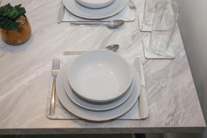 a table with white plates and silverware on it at Cosy 2-bed home - For Company contractor and Leisure stays - NEC, Airport, HS2, Contractors, Resort World in Marston Green +29 photos