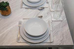 a table with white plates and silverware on it at Cosy 2-bed home - For Company contractor and Leisure stays - NEC, Airport, HS2, Contractors, Resort World in Marston Green