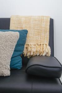 a black couch with a pillow and a blanket at Cosy 2-bed home - For Company contractor and Leisure stays - NEC, Airport, HS2, Contractors, Resort World in Marston Green
