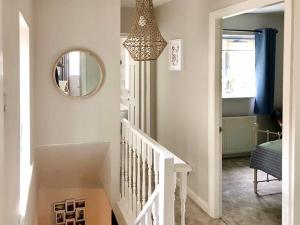 pasillo con escalera con espejo y lámpara de araña en Spring Cottage, en Parkgate