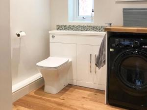 a bathroom with a toilet and a washing machine at Spring Cottage in Parkgate