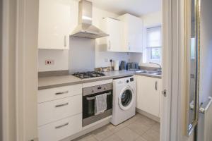 a kitchen with white cabinets and a washer and dryer at Cosy 2-bed home - For Company contractor and Leisure stays - NEC, Airport, HS2, Contractors, Resort World in Marston Green