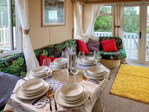 een woonkamer met een tafel met borden en wijnglazen bij Retro Retreat in Goodrington