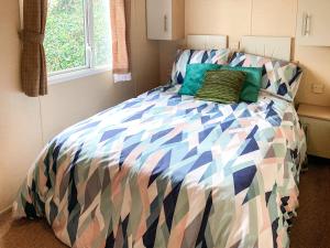 a bed with a colorful comforter in a bedroom at Retro Retreat in Goodrington