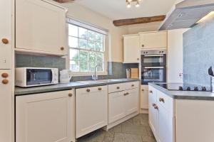 una cocina con armarios blancos y una ventana en The Old Post Cottage, Coniston, en Coniston