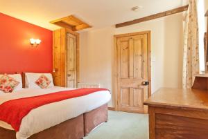 1 dormitorio con cama y escritorio de madera en The Old Post Cottage, Coniston, en Coniston