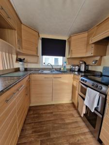 a kitchen with wooden cabinets and a stove top oven at Caravan in the Cotswolds in Cirencester
