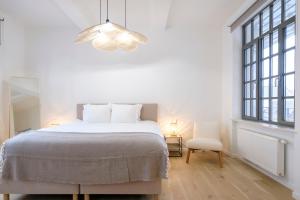 een witte slaapkamer met een bed en een groot raam bij Magnifique Appartement 3 chambres vue Théâtre de la Monnaie in Brussel