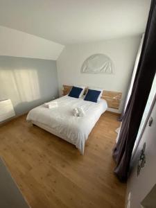 um quarto com uma cama com lençóis brancos e almofadas azuis em Villa nature - spacieuse et moderne em Villemer