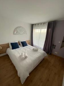 ein Schlafzimmer mit einem großen weißen Bett mit blauen Kissen in der Unterkunft Villa nature - spacieuse et moderne in Villemer