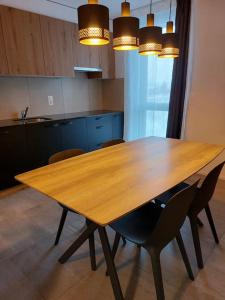 - une table en bois dans une cuisine avec des chaises et des lumières dans l'établissement Appartement 2p1/2 pour couple ou famille, à Romont