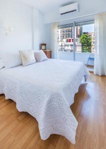 uma cama branca com um cobertor branco num piso de madeira em La mejor zona de Palermo. Bruna em Buenos Aires