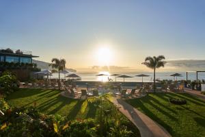 a resort with chairs and umbrellas and the ocean at Les Suites at The Cliff Bay - PortoBay in Funchal