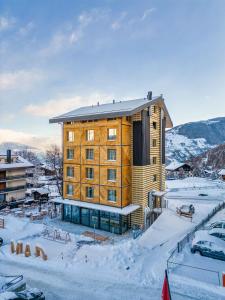 a large wooden building in the snow with cars parked at MAD Mount Hotel & Spa in Nendaz
