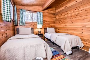 Dos camas en un dormitorio tipo cabaña de troncos con paredes de madera. en Behnkes Bungalow, en Manitowish Waters