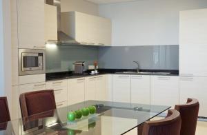 a kitchen with white cabinets and white appliances at Millennium Executive Apartments Muscat in Muscat