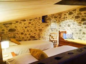 1 dormitorio con 2 camas y pared de piedra en Terre et Eau gite La Flocellière, en La Flocellière