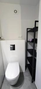 a bathroom with a white toilet and a black shelf at Siódme Niebo in Wrocław