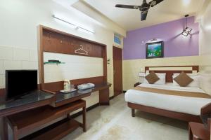 a bedroom with a bed and a desk with a television at Mannars Yatri Nivas Hotel in Mysore