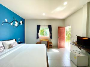 1 dormitorio con 1 cama blanca y paredes azules en Be Leaf Resort SHA, en Thalang