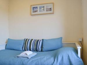 a blue bed with a towel on top of it at Gwyrfai Cottage in Waenfawr