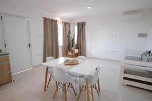 a white dining room with a white table and chairs at Cabaña 1920 - frente a viñedo in San Rafael
