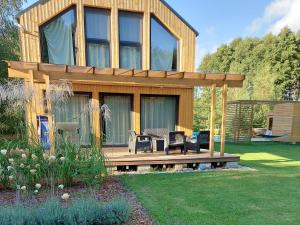 una casa con terraza de madera en un patio en Dom przy lesie en Wielgie