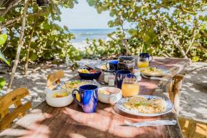 drewniany stół z talerzami jedzenia i napojów na plaży w obiekcie Lote 10 Glamping w mieście Guachaca